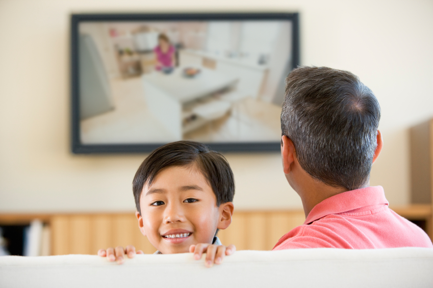 man and boy watching tv in living room