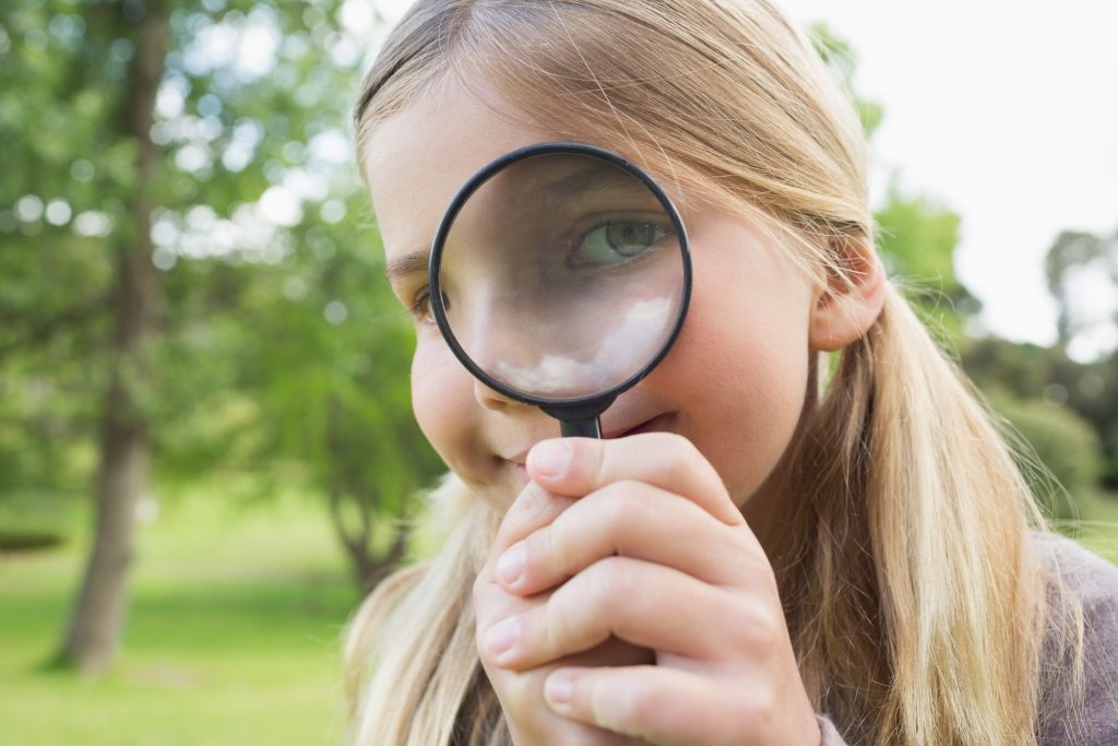 Close-up of a girl looking out of a magnifying glass