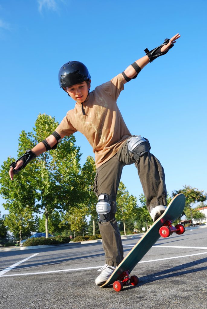 A boy does a skateboard trick while wearing a helmet and additional protective equipment