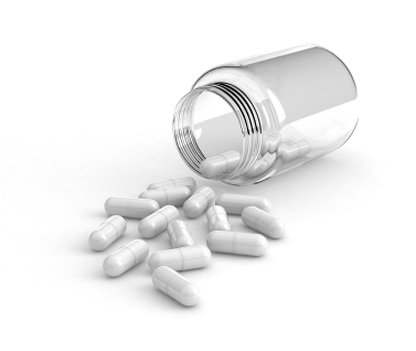 White capsule pills spilling out of a glass container